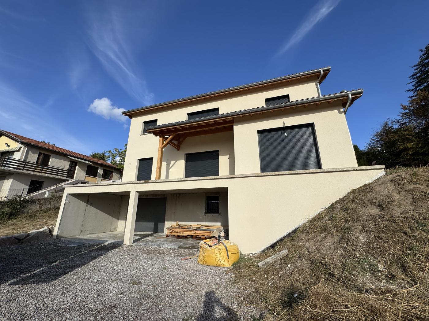 Maison neuve sur terrain en pente, enduit crème